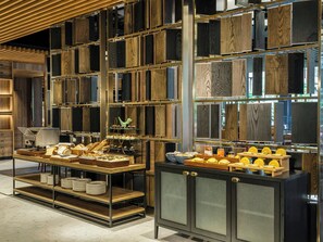 A modern interior with a wooden panel wall, a display counter with food items, and a glass-fronted cabinet. - voco Bangkok Surawong by IHG (Bangkok)