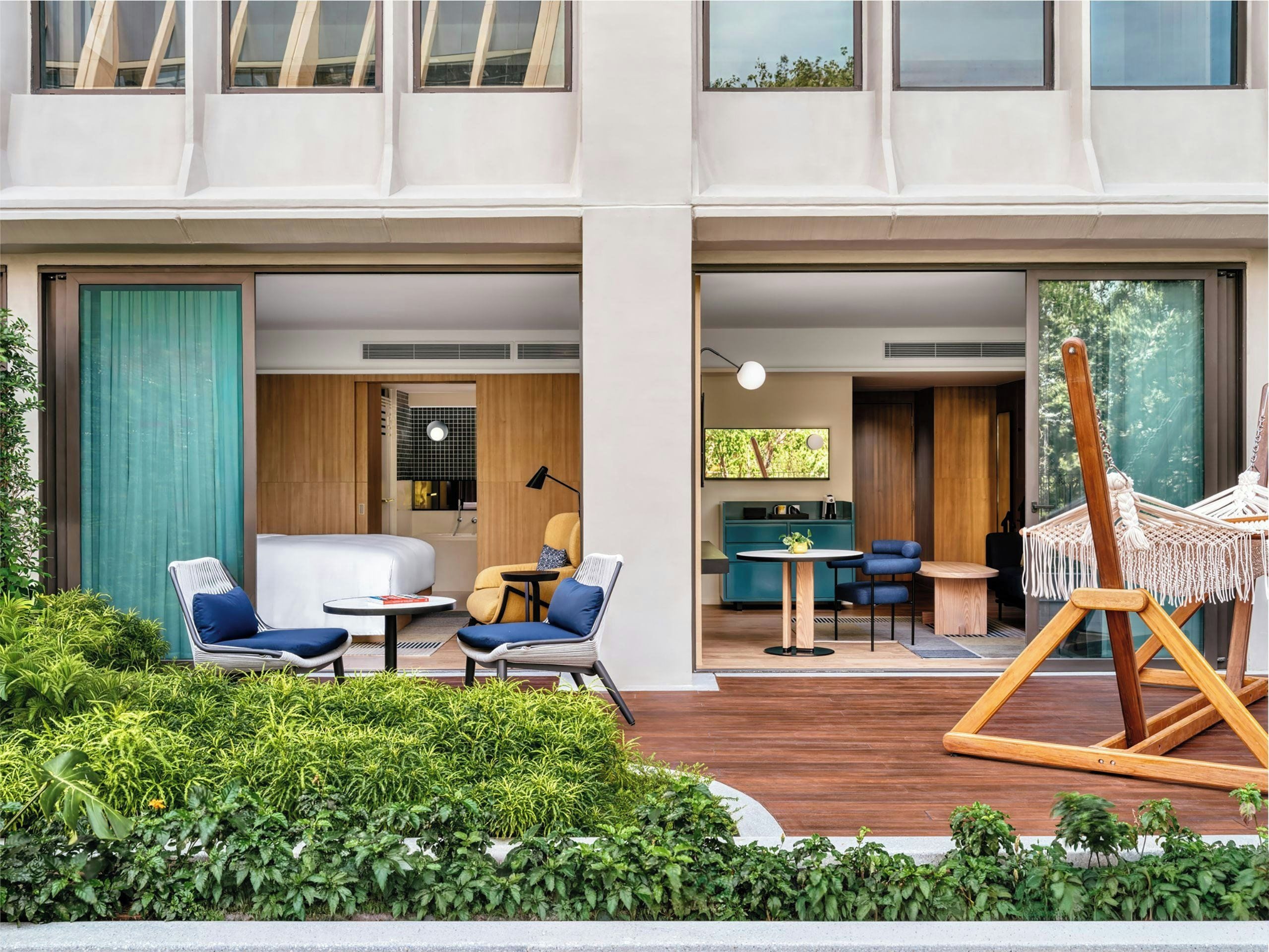 Habitación de hotel moderna con cama, zona de estar y vista a la vegetación.