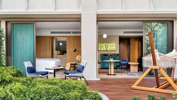 Habitación de hotel moderna con cama, zona de estar y vista a la vegetación.