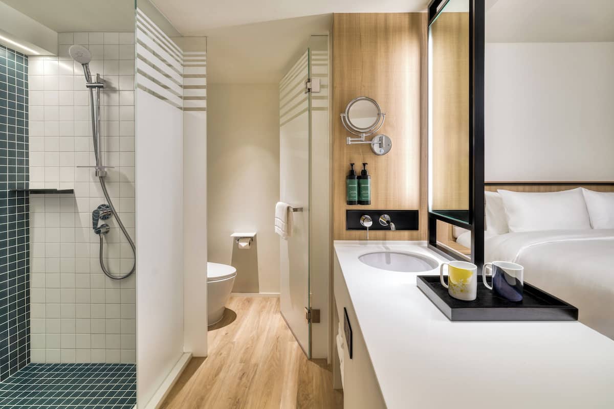 Un baño moderno con ducha, inodoro, lavamanos y un espejo grande.