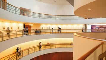 A multi-level atrium with glass railings, artwork on the walls, and people walking.