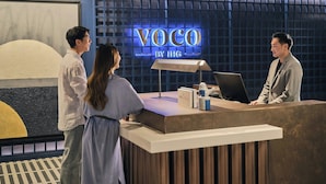 Un mostrador de recepción con un cartel que dice 'VOCO BY IHG' en el vestíbulo de un hotel.