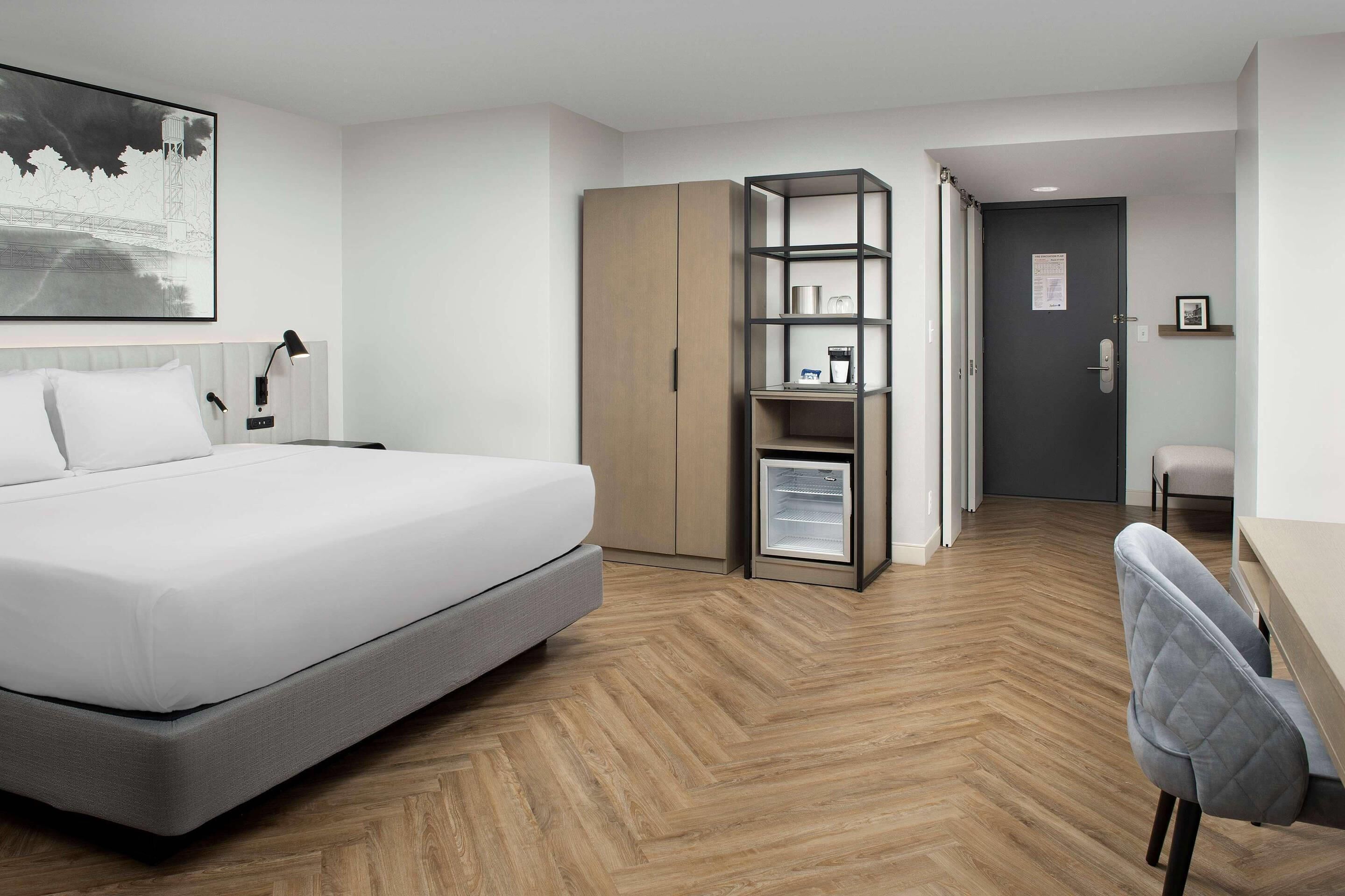 Una habitación de hotel con cama, armario, escritorio y silla.