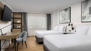 A hotel room with two beds, a desk with a chair, a TV mounted on the wall, and artwork on the walls. - Radisson Blu Fargo (Fargo)