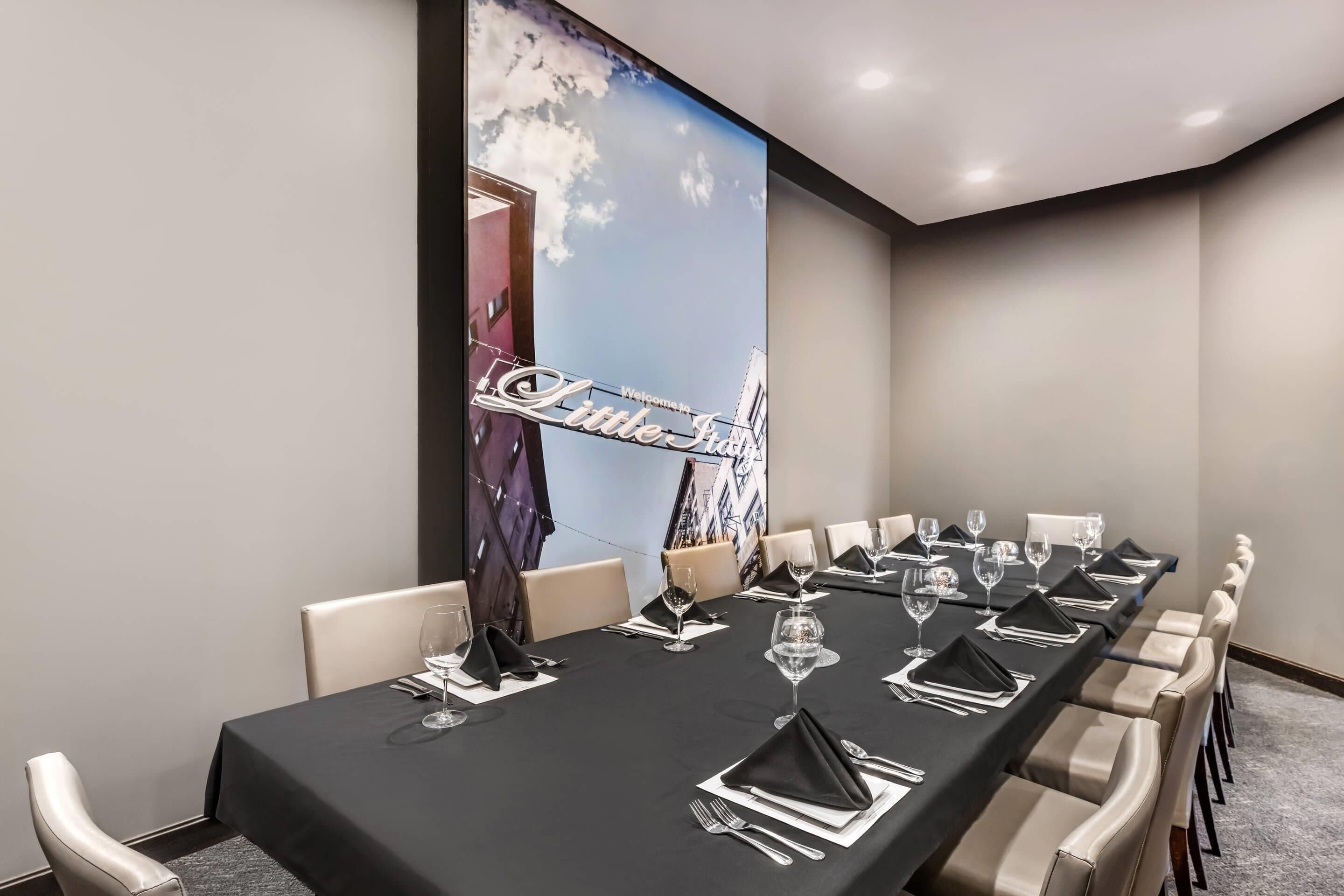 A conference room with a long table set for a meeting, a 'Welcome' sign, and a cityscape mural on the wall.