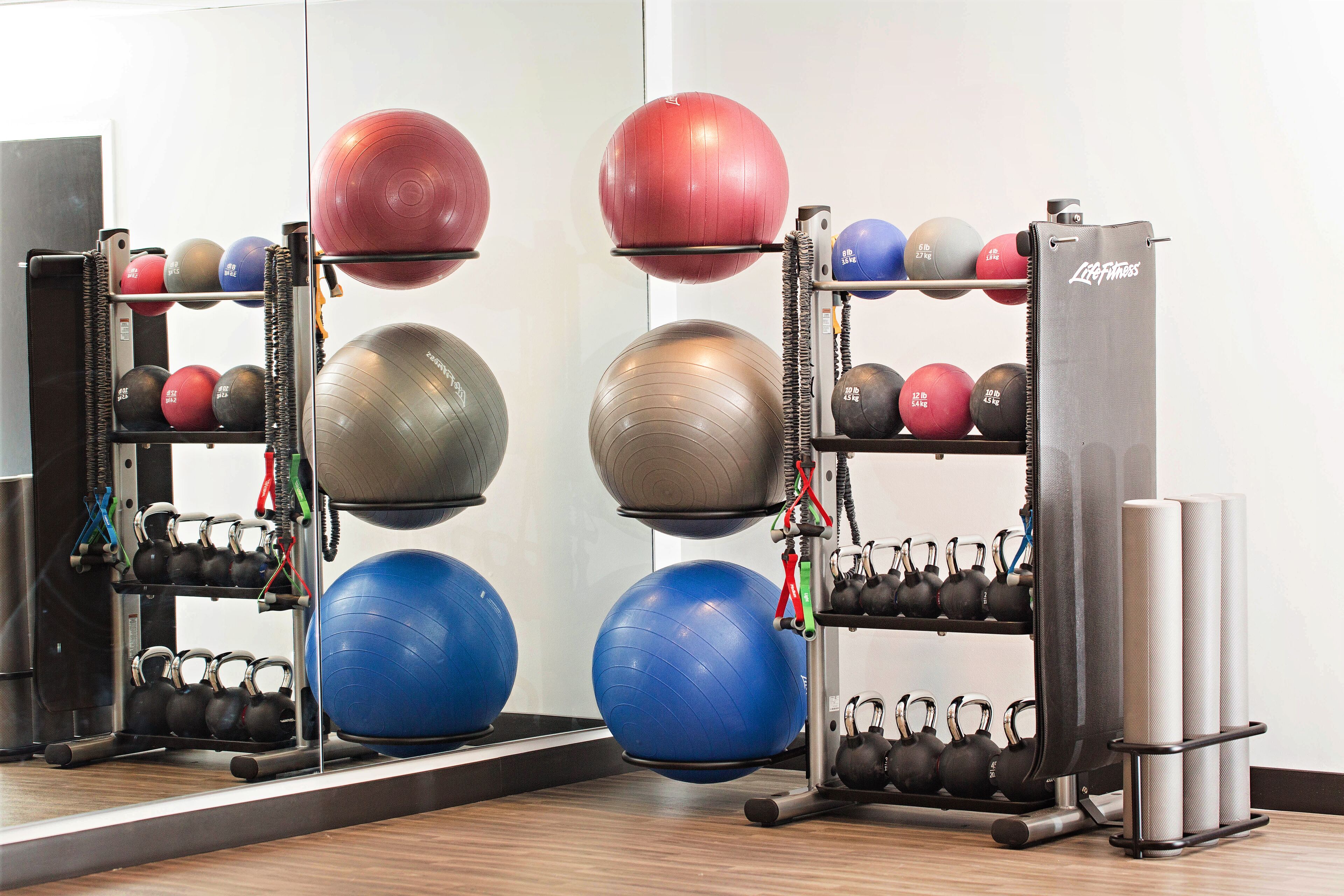 A gym with exercise equipment including kettlebells, medicine balls, and a weight rack.