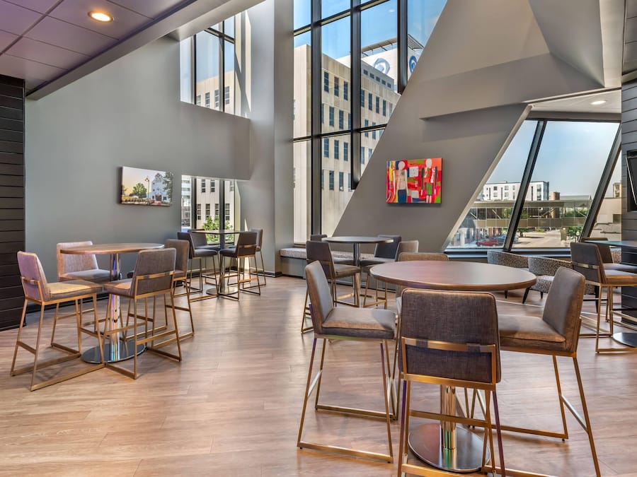 Un intérieur moderne avec de hauts plafonds, de grandes fenêtres et différents types de mobilier, notamment des tables et des chaises.
