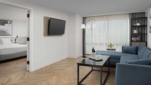 A modern hotel room with a bed, a TV, a sofa, a coffee table, and a bookshelf. - Radisson Blu Fargo (Fargo)
