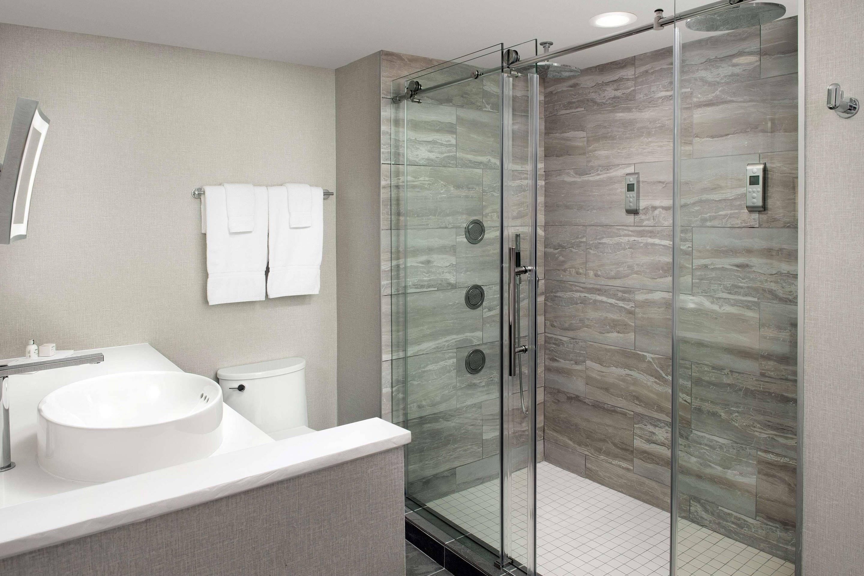 Une salle de bain moderne avec une douche à parois de verre, un lavabo blanc et des toilettes.