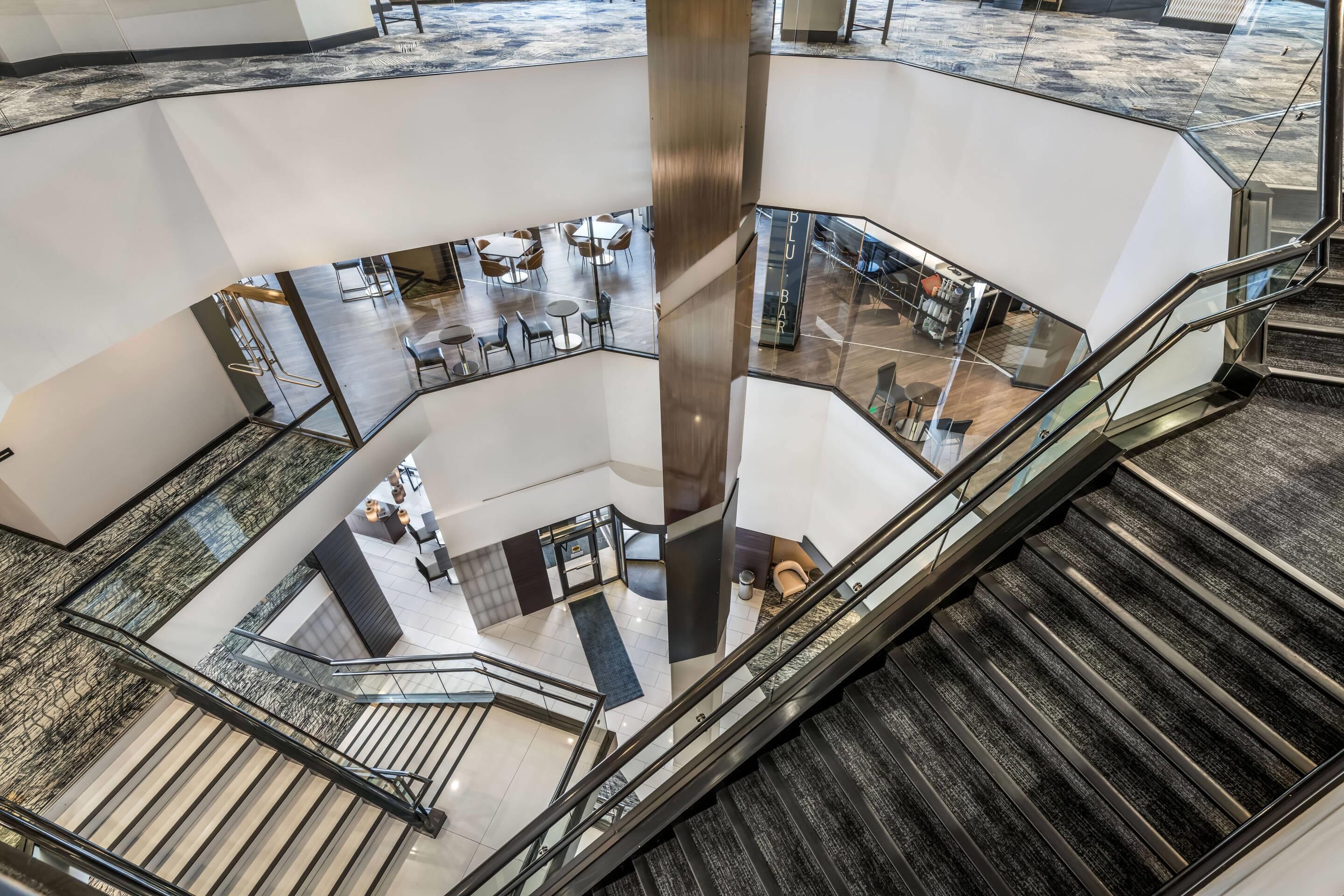 Un intérieur à plusieurs niveaux doté d’un puits d’ascenseur central en verre, de plusieurs espaces de détente et d’un escalier.