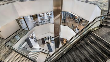 Un intérieur à plusieurs niveaux doté d’un puits d’ascenseur central en verre, de plusieurs espaces de détente et d’un escalier.