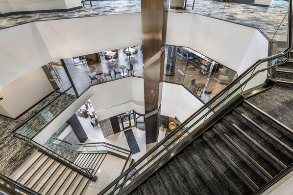 A multi-level interior with a central glass elevator shaft, multiple seating areas, and a staircase. - Radisson Blu Fargo (Fargo)