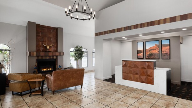 A spacious lobby with a fireplace, a reception desk, and a large chandelier.