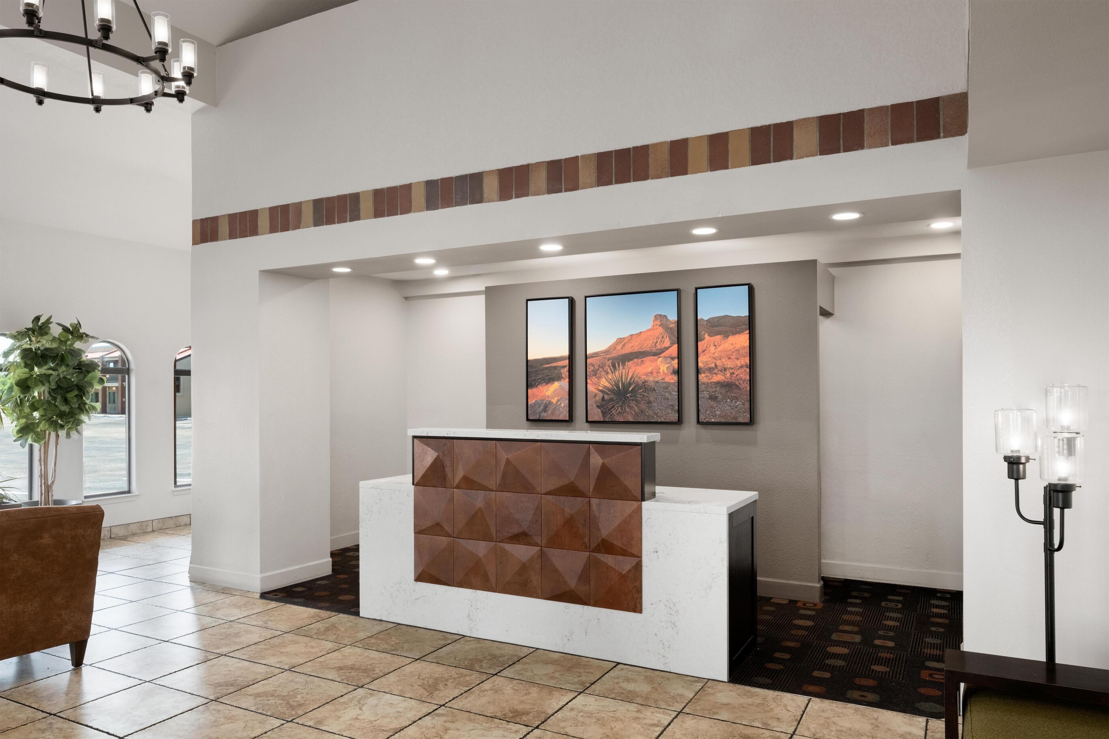 A reception area with a modern design, featuring a reception desk, a potted plant, and framed artwork on the wall.