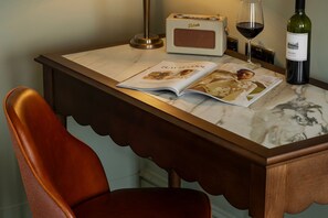 A table with a magazine, a wine glass, a bottle of wine, and a radio. - Castle Hotel Windsor (Windsor)