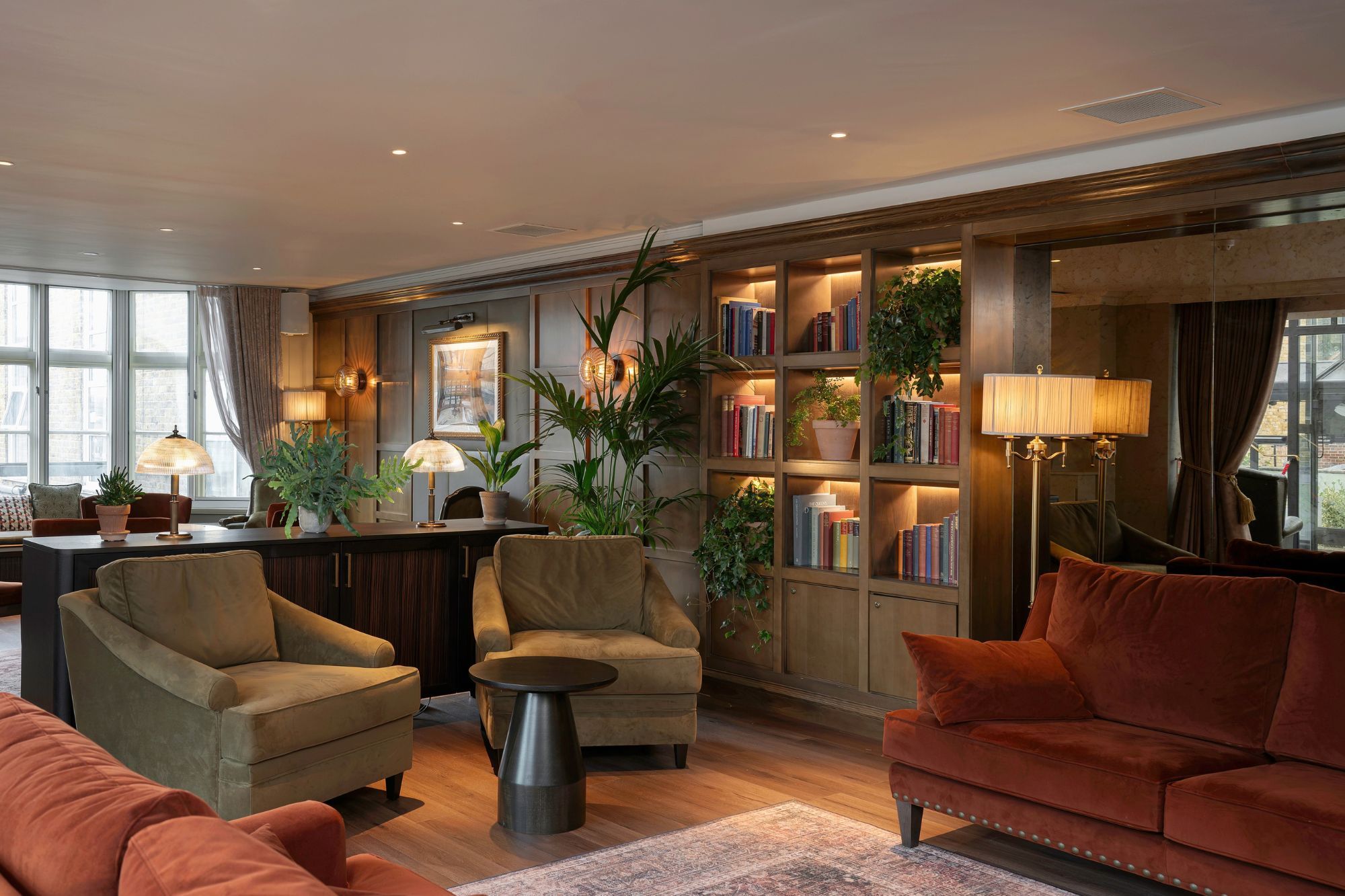 A modern living room with sofas, a coffee table, and a bookshelf filled with books and plants.