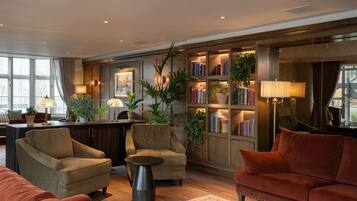 A modern living room with sofas, a coffee table, and a bookshelf filled with books and plants.
