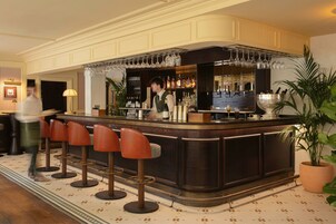 A bar area with stools, a bartender, and a variety of bottles and glasses.