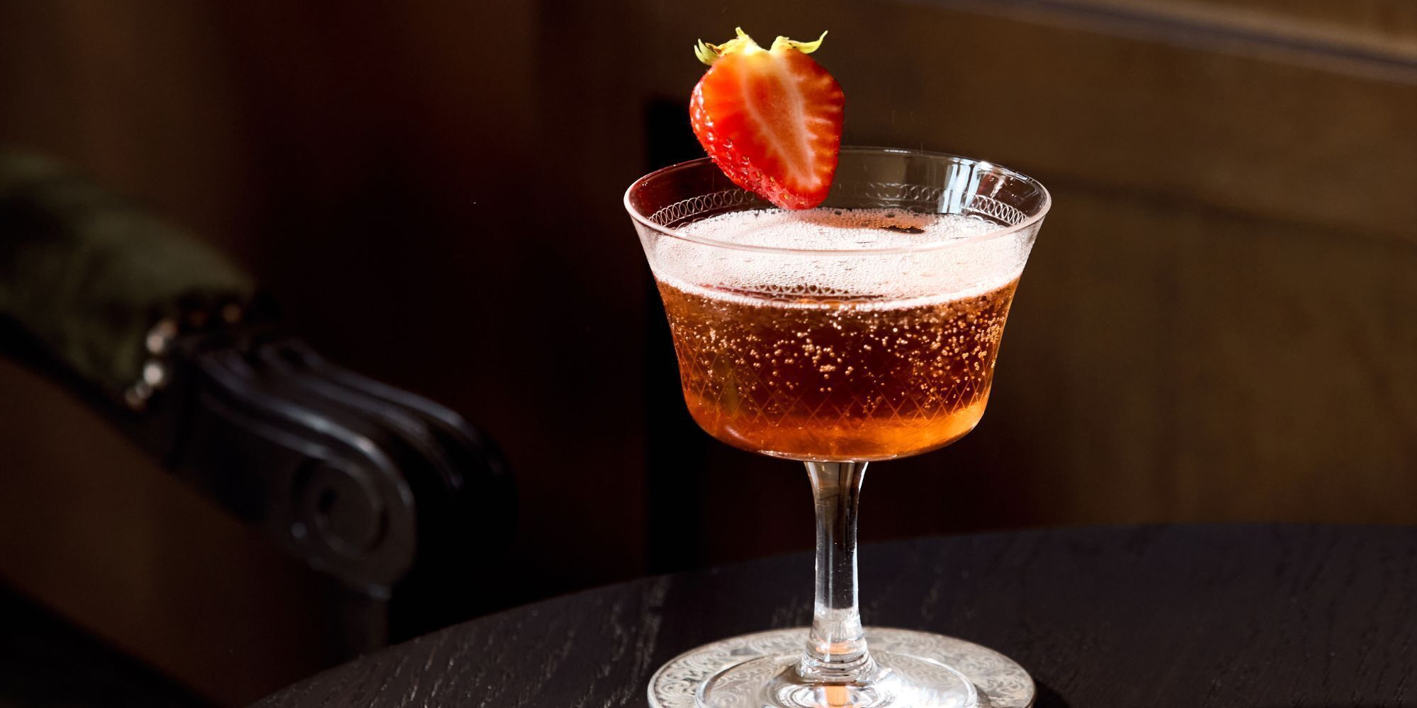 A cocktail in a glass with a strawberry garnish.