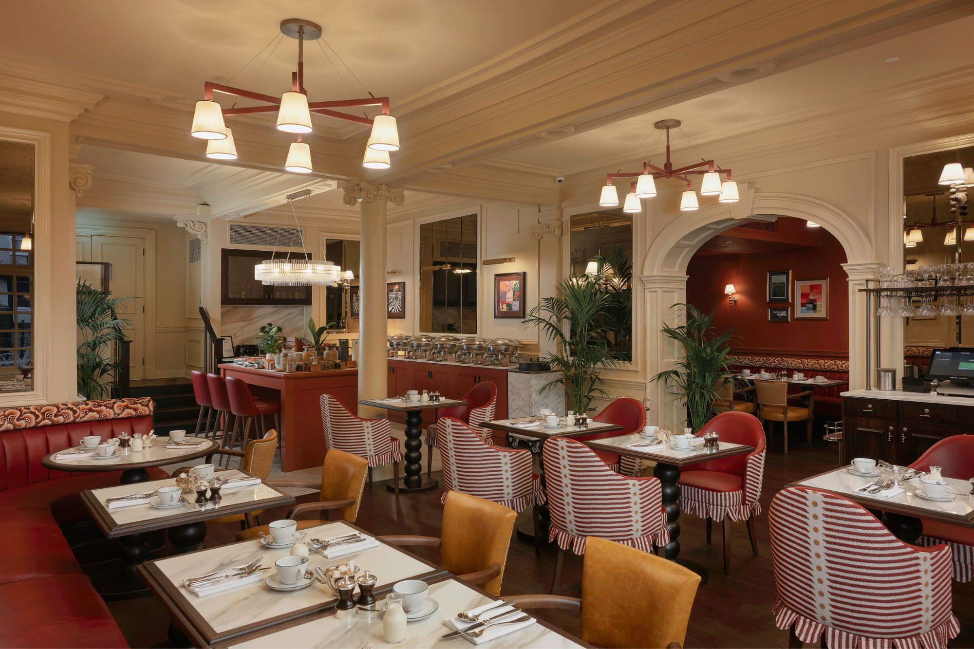 A restaurant with multiple dining tables, red upholstered booths, and a bar area.