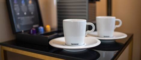 Two white Nespresso cups on saucers on a black tray.