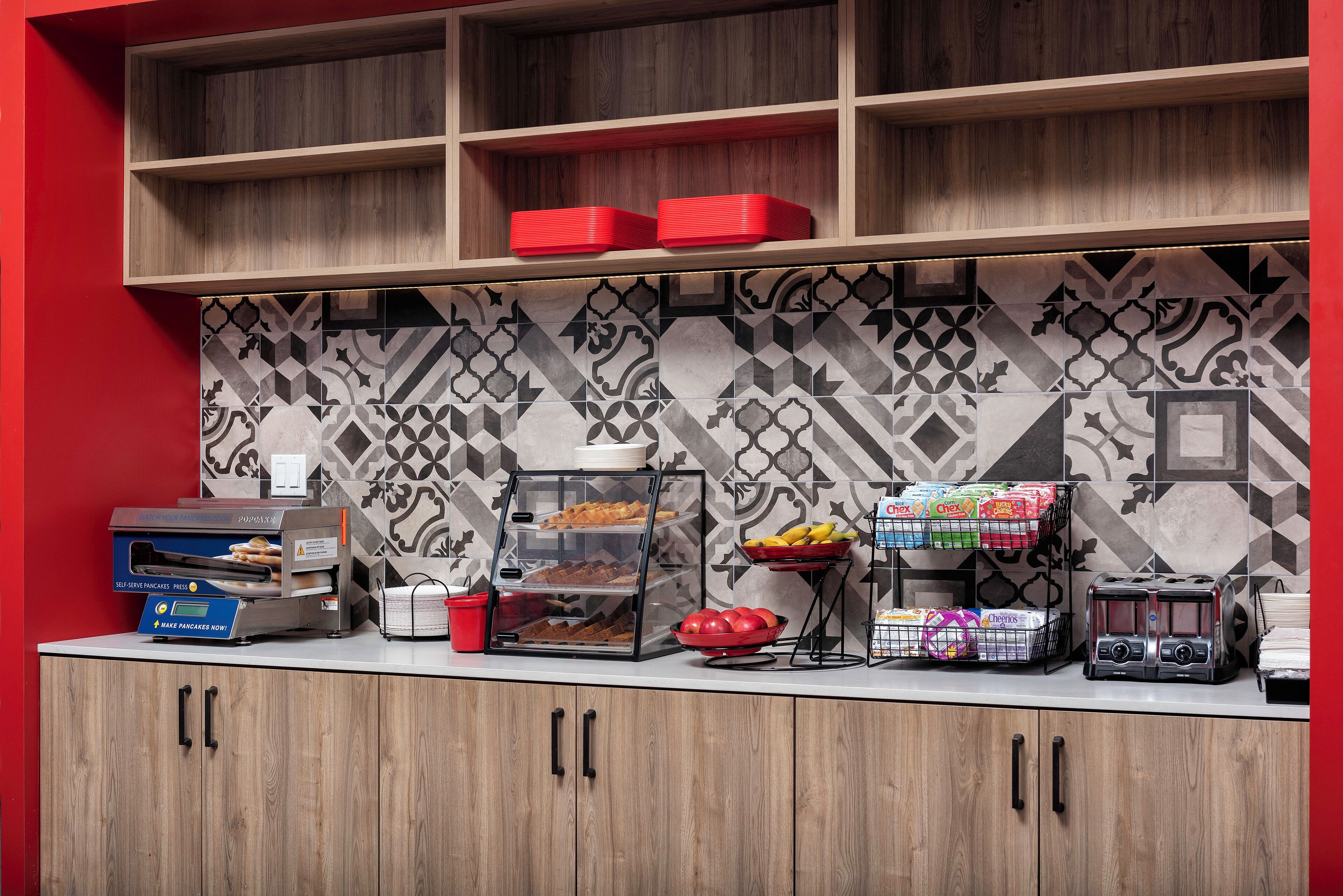 A breakfast bar with a self-serve pancake station, a fruit bowl, and a coffee station.