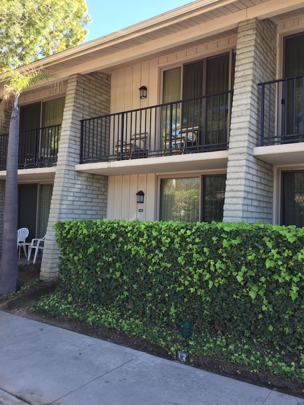A two-story building with a balcony on the second floor, a hedge in front, and a white door. - Ramada by Wyndham Santa Barbara (Santa Barbara)