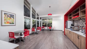 A modern kitchen with red chairs, a large window, and a wooden counter.