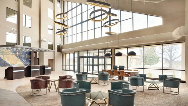 A spacious lobby with modern furniture, large windows, and a reception area. - Holiday Inn Bloomington - Normal by IHG (Normal)