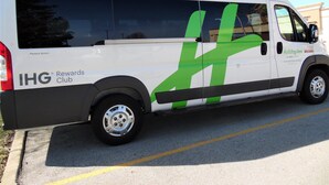 A white van with green and black graphics, advertising IHG Rewards Club and holidayinn.com. - Holiday Inn Bloomington - Normal by IHG (Normal)