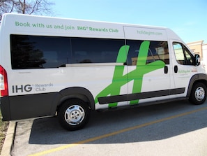 Een witte bus met groene en zwarte afbeeldingen, reclame maakt voor IHG Rewards Club en holidayinn.com.