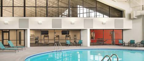 An indoor swimming pool with a high ceiling and large windows.