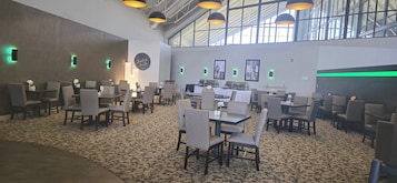 Un espace intérieur vaste et lumineux, doté de nombreuses tables et chaises, d’un tapis à motifs et d’un plafond haut laissant entrer la lumière naturelle.