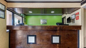 A reception desk with a green wall, framed certificates, and a red carpet with the EconoLodge logo. - Econo Lodge Nashville near Percy Priest Lake (Nashville)