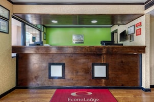 A reception desk with a green wall, framed certificates, and a red carpet with the EconoLodge logo.