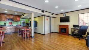 A spacious room with wooden flooring, a kitchen area with wooden cabinets, a fireplace, and a television mounted on the wall. - Econo Lodge Nashville near Percy Priest Lake (Nashville)