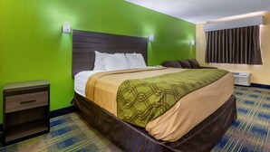 A hotel room with a green wall, a wooden headboard, a bed with white and beige bedding, a nightstand, and a window with curtains. - Econo Lodge Nashville near Percy Priest Lake (Nashville)