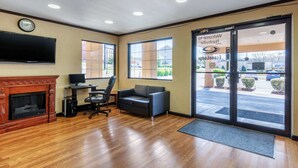 A hotel lobby with a fireplace, a television, a sofa, a desk with a computer, and large windows offering a view of the parking lot. - Econo Lodge Nashville near Percy Priest Lake (Nashville)