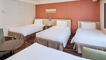A hotel room with two single beds, a small table, and a chair.