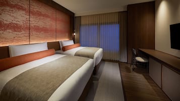 A hotel room with two beds, a desk, and a TV.
