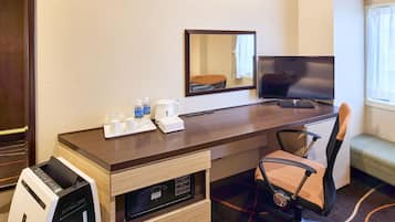 Habitación de hotel con escritorio de madera, una silla, televisor, espejo, cafetera y microondas.