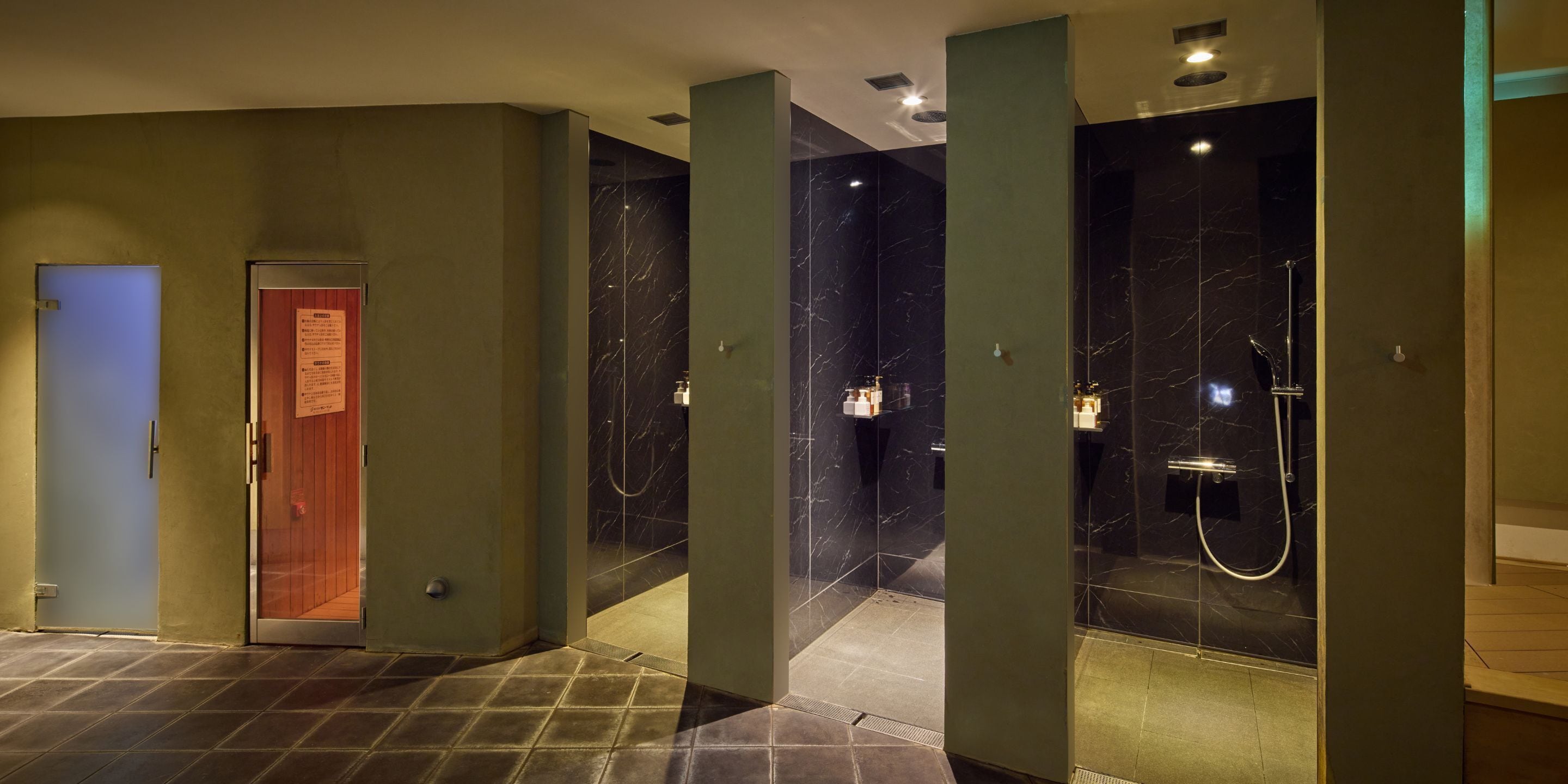 Une salle de bain moderne avec des murs en marbre, un espace douche et une porte avec une pancarte.