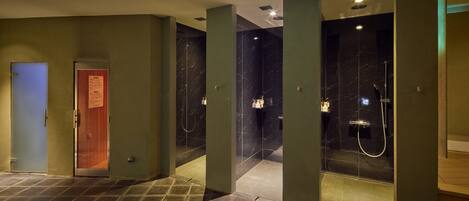A modern bathroom with marble walls, a shower area, and a door with a sign.