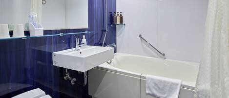 A modern bathroom with a white sink, a bathtub, and a glass shower enclosure.