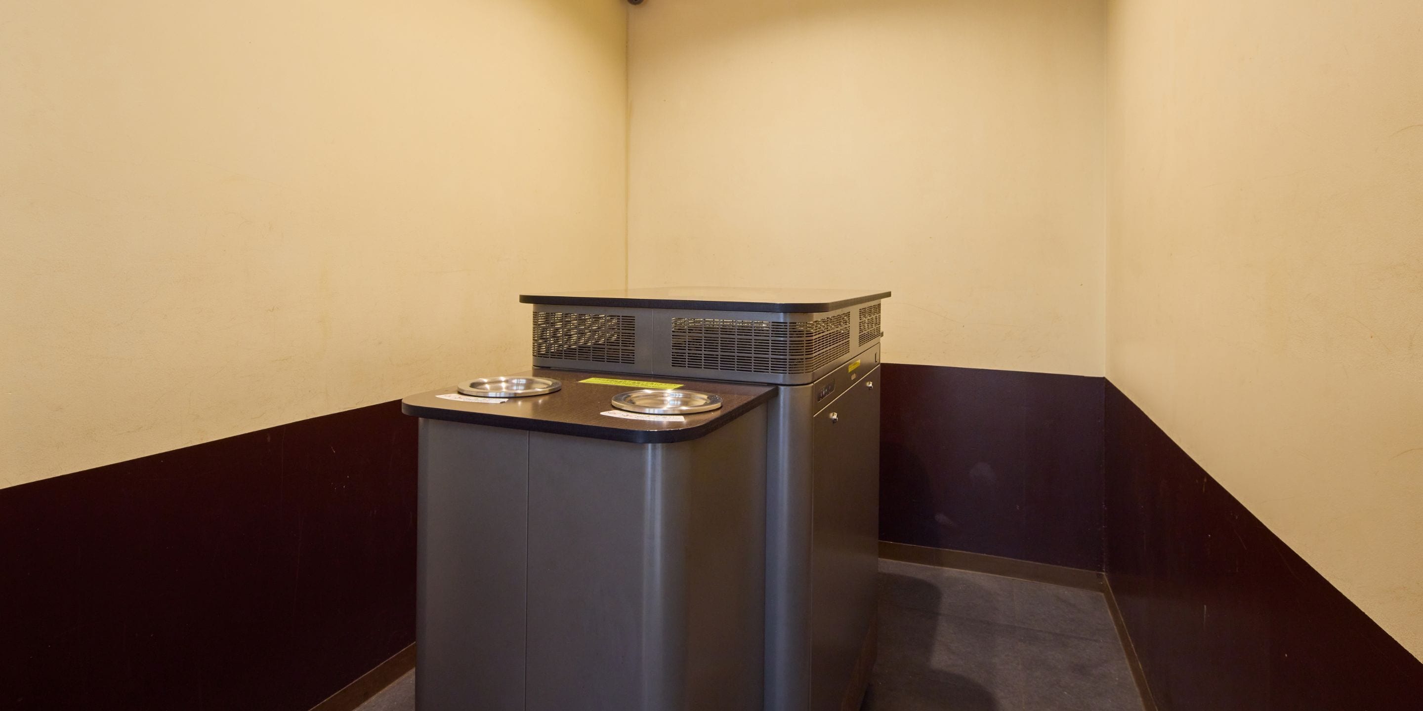 A compact kitchenette with a built-in stove, two stainless steel sinks, and a small trash bin.