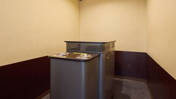 A compact kitchenette with a built-in stove, two stainless steel sinks, and a small trash bin.