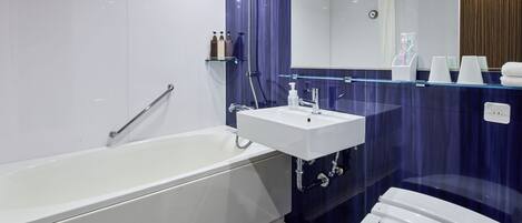A modern bathroom with a white bathtub, a glass-enclosed sink, and a large mirror above the sink.