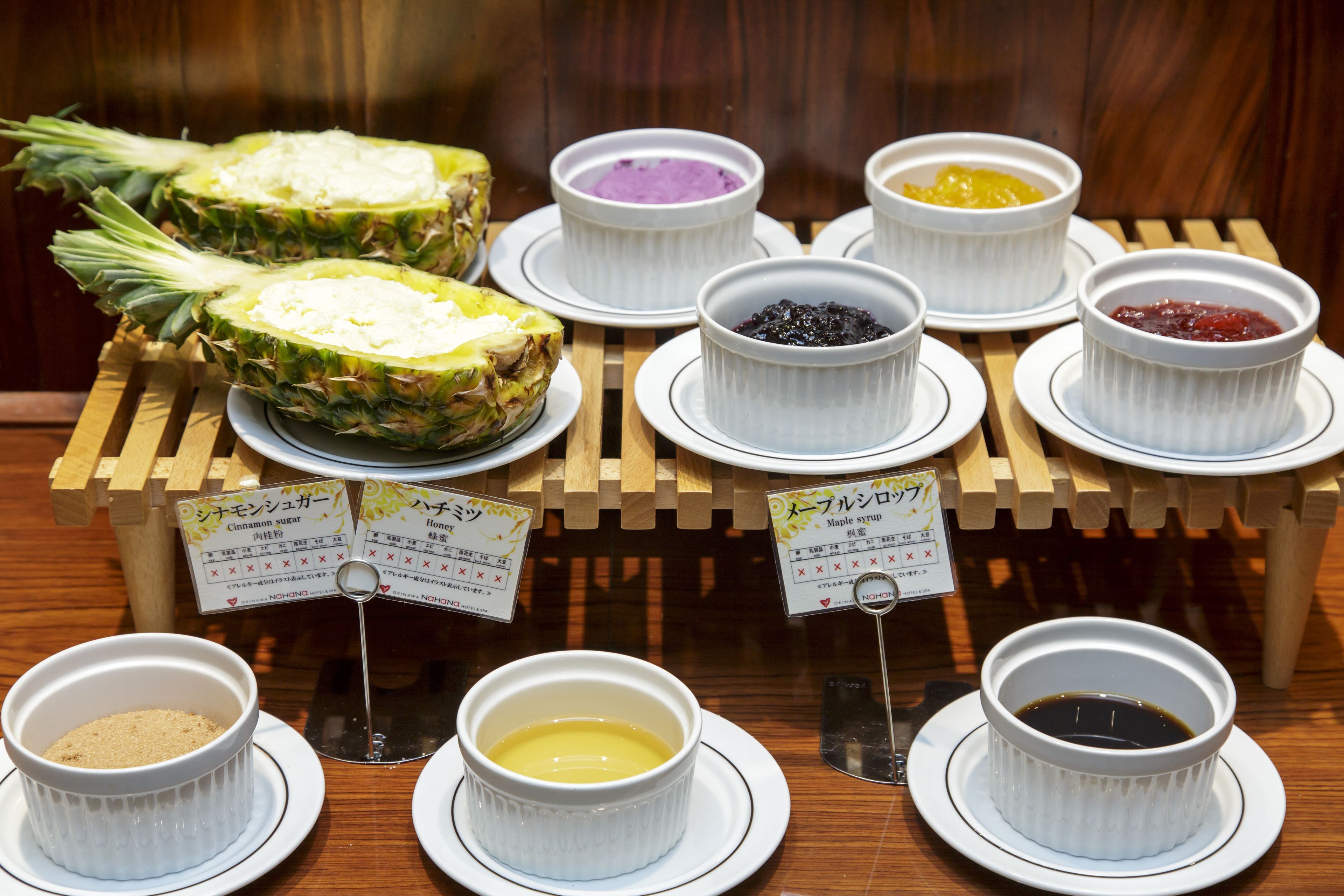 A display of various food items including pineapple, bowls of different sauces, and a sign with prices.