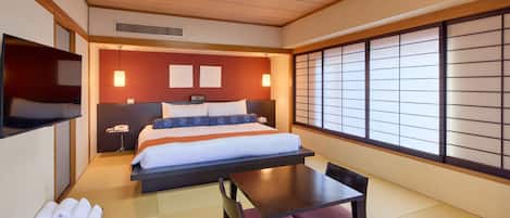 Habitación de hotel con cama, mesita de noche, silla y vistas a través de un panel shoji.