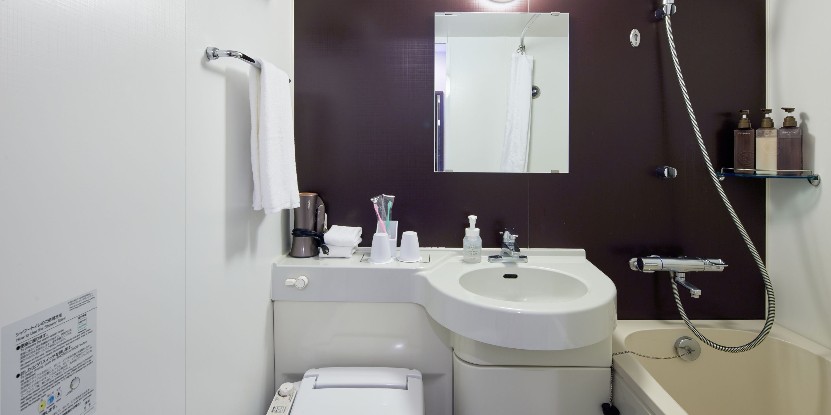 Un baño con lavamanos blanco, un espejo, toallero, ducha y estante con artículos de aseo.
